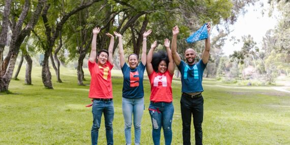 Empowered team members celebrating together outdoors with their arms raised in the air.